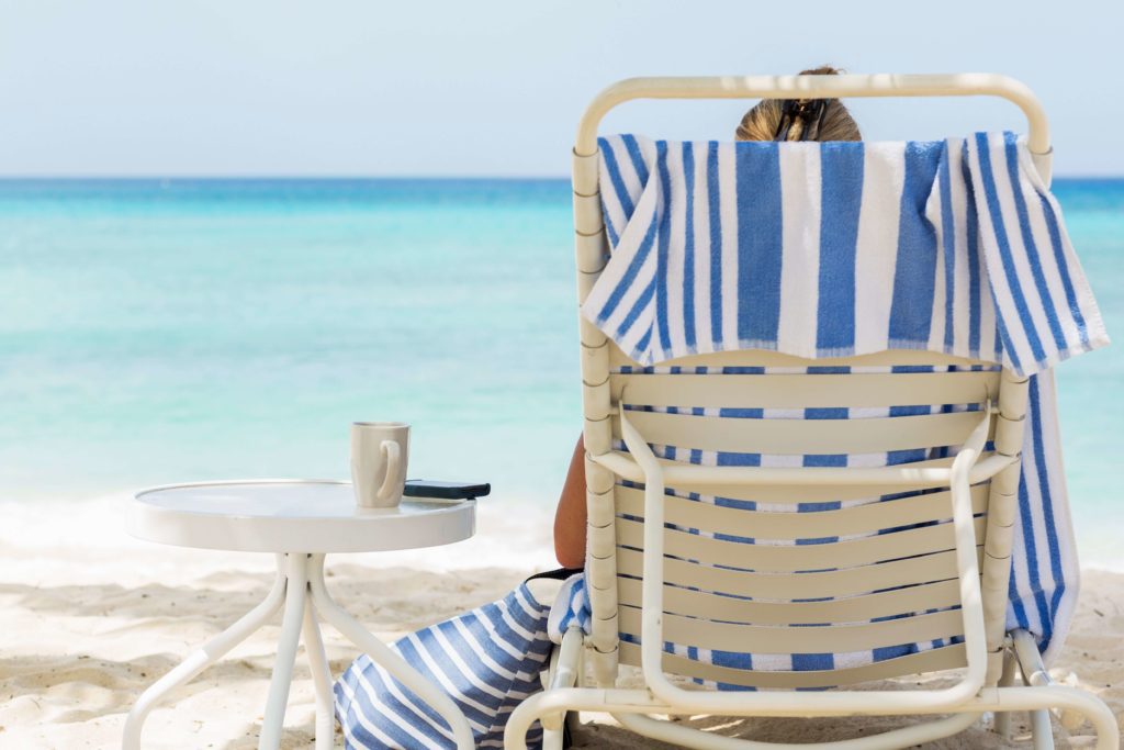 As person in a chair enjoying one of Grand Cayman beaches.
